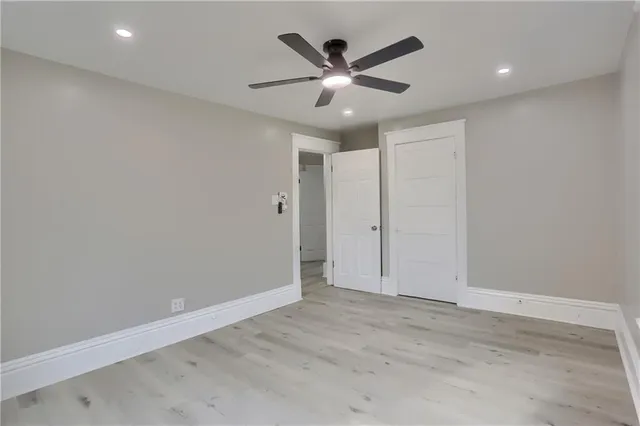 an empty room with a ceiling fan and wooden floor