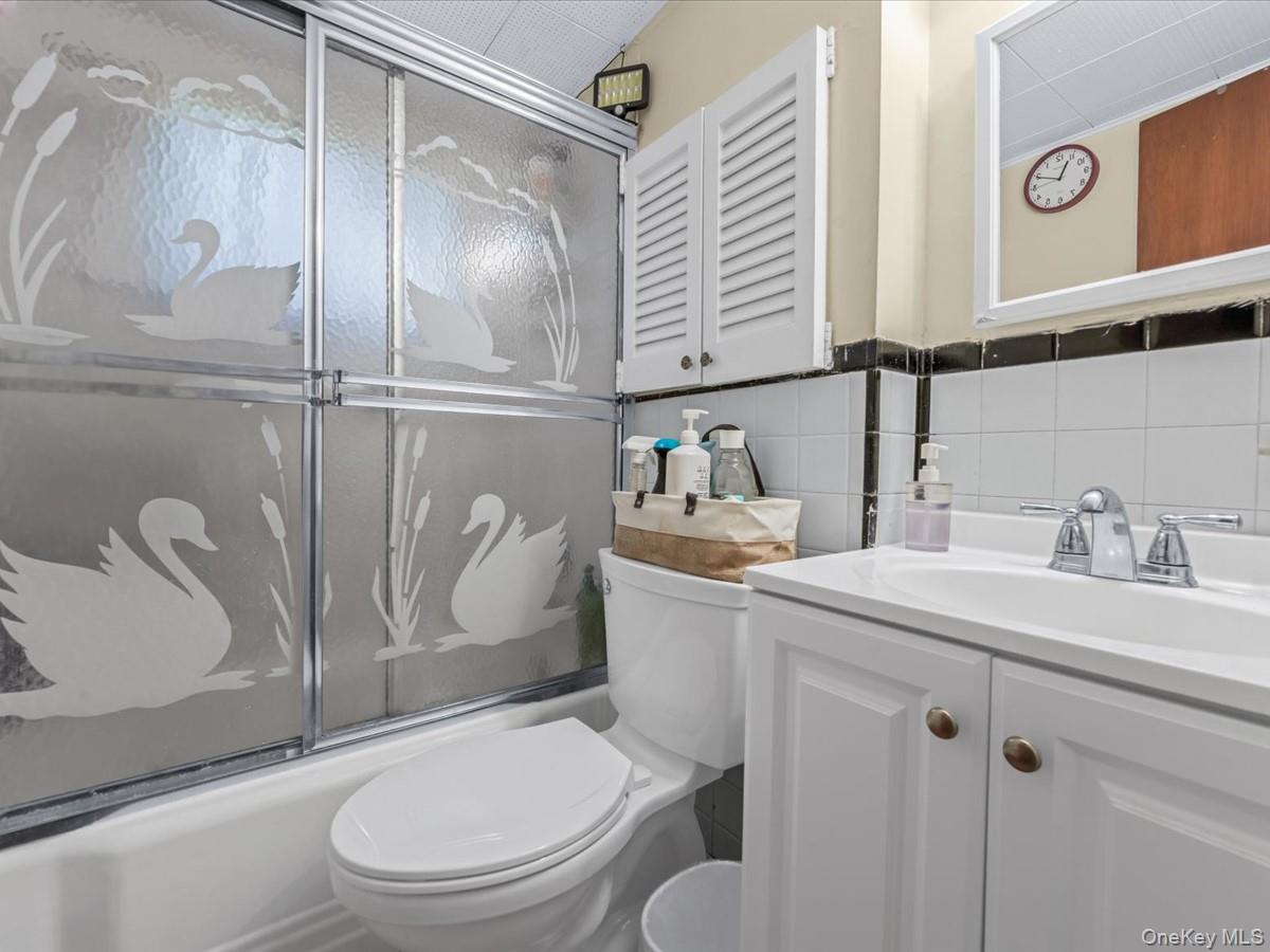 205 Lenox Road Huntington Station, NY 11746 - Photo 20 of 25 Full bathroom featuring vanity, tile walls, and enclosed tub / shower combo