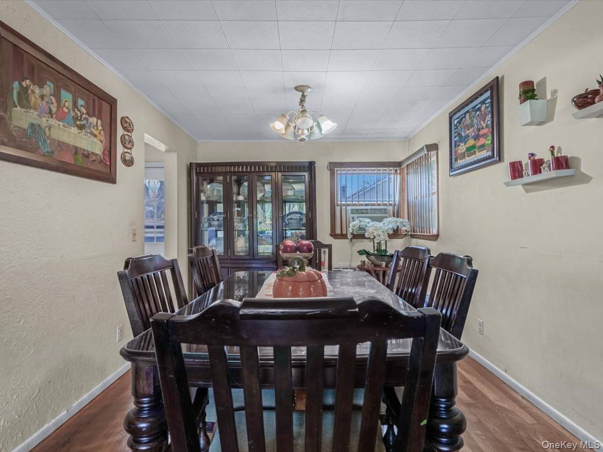 205 Lenox Road Huntington Station, NY 11746 - Photo 5 of 25 Dining area with ornamental molding, a textured wall, a chandelier, and dark wood finished floors