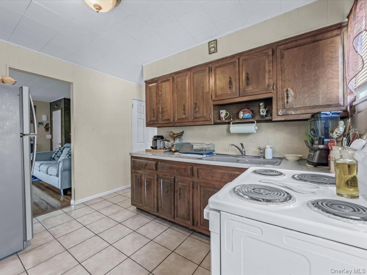 205 Lenox Road Huntington Station, NY 11746 - Photo 7 of 25 Kitchen with white electric range oven, light countertops, freestanding refrigerator, light tile patterned flooring, and open shelves
