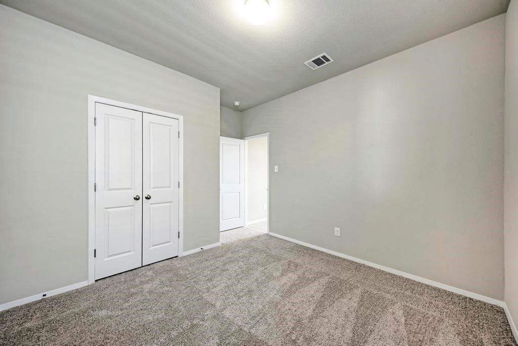 1209 Goforth Road Kyle, TX 78640 - Photo 26 of 32 A well-proportioned bedroom with ample natural light, featuring plush carpeting and a convenient closet.