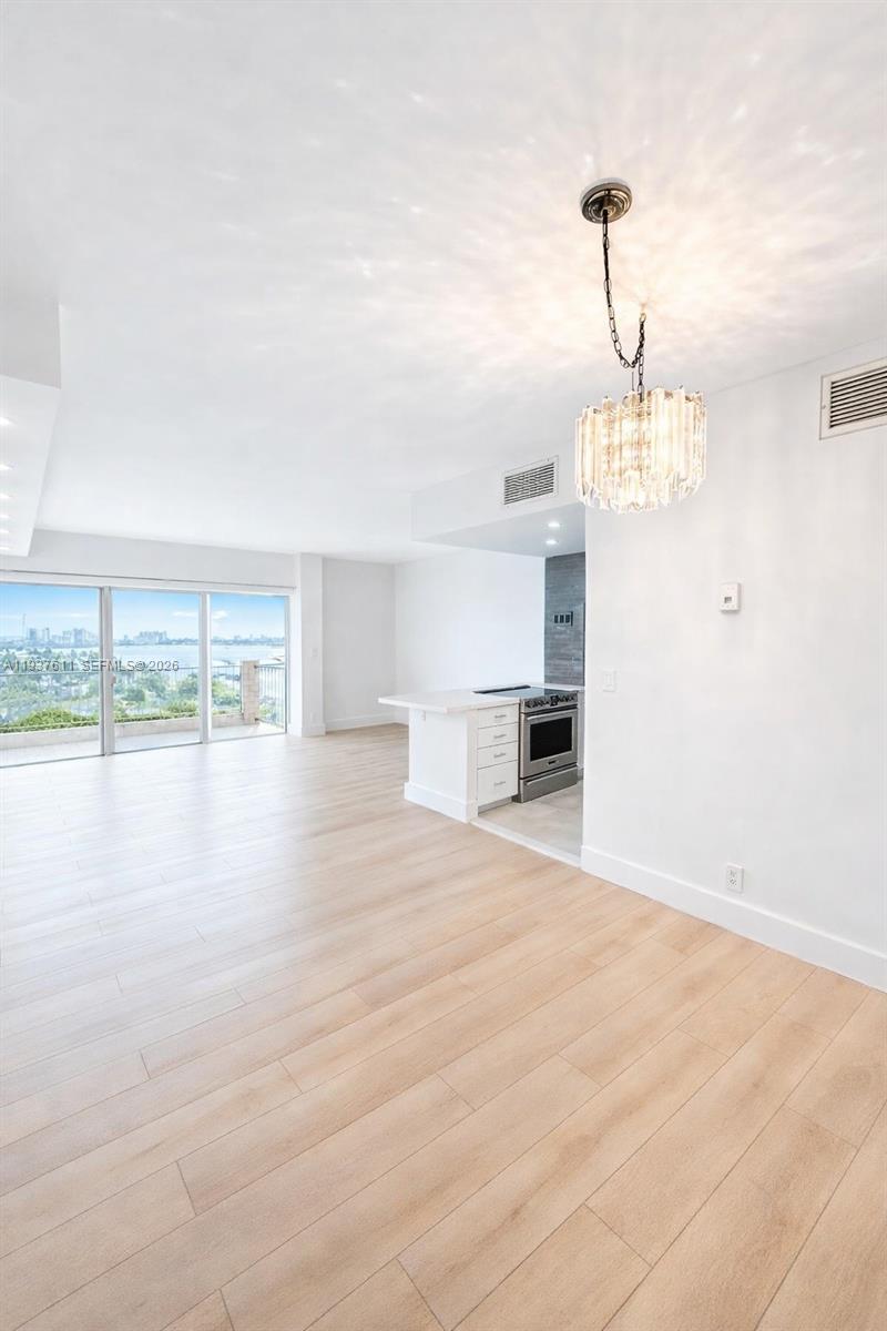 880 Northeast 69th Street, Unit 8M Miami, FL 33138 - Photo 3 of 14 a view of empty room with wooden floor and windows
