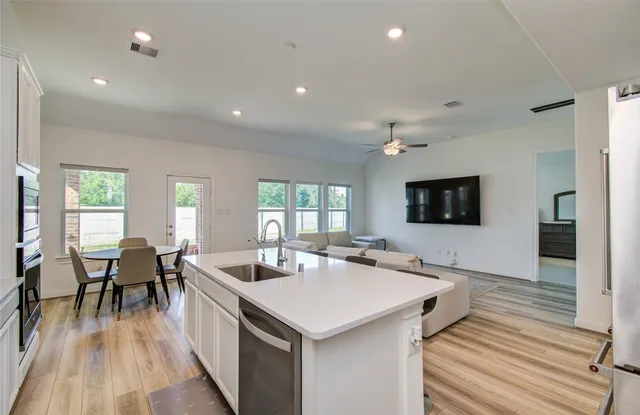 a living room with stainless steel appliances kitchen island granite countertop a sink a counter space and living room view