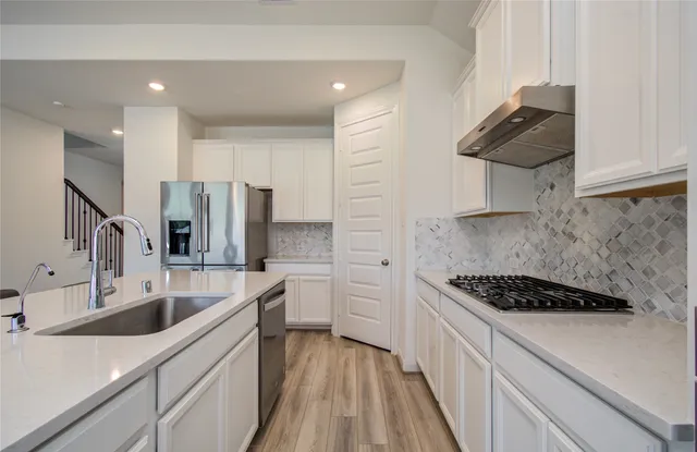 a kitchen with stainless steel appliances a sink stove and refrigerator