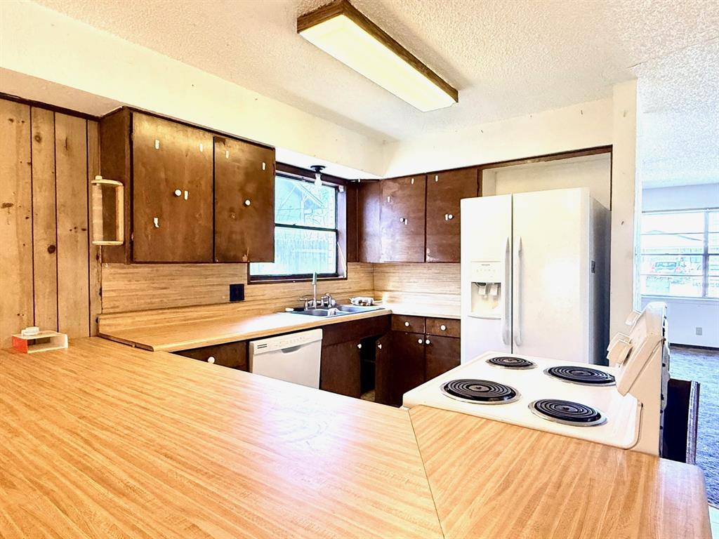 1954 East Booth Street Paris, TX 75460 - Photo 2 of 11 a kitchen with stainless steel appliances granite countertop a refrigerator a stove and a sink with wooden floor