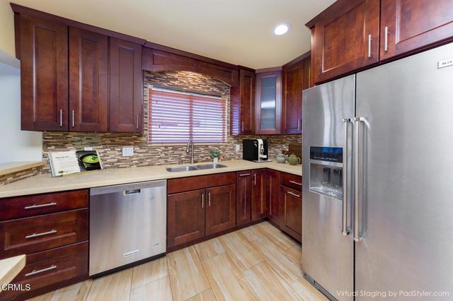 a kitchen with stainless steel appliances granite countertop wooden cabinets a refrigerator and a sink