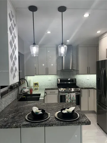 a kitchen with granite countertop white cabinets and stainless steel appliances