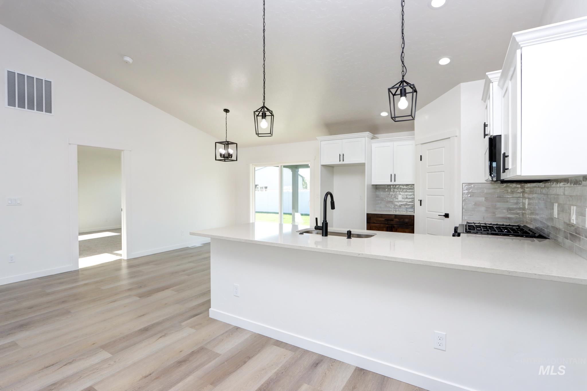 848 North 5th Street Nyssa, OR 97913 - Photo 1 of 49 Modern kitchen featuring white cabinetry, a light-toned countertop, a black gooseneck faucet, and a subway tile backsplash