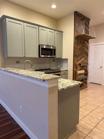a kitchen with kitchen island granite countertop a stove a sink and a microwave