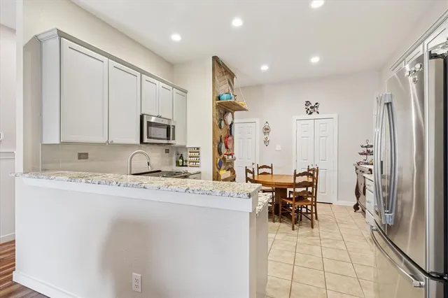 a kitchen with stainless steel appliances kitchen island granite countertop a refrigerator and a sink