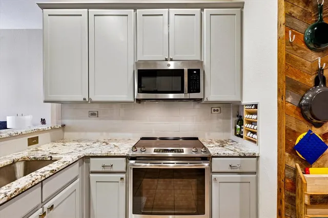 a kitchen with granite countertop white cabinets and black appliances