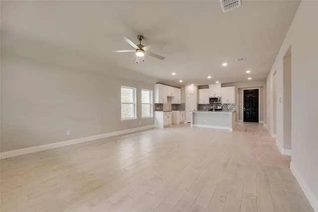 a view of an empty room with kitchen view and a window