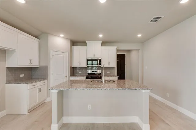 a large kitchen with a large counter top stainless steel appliances and cabinets