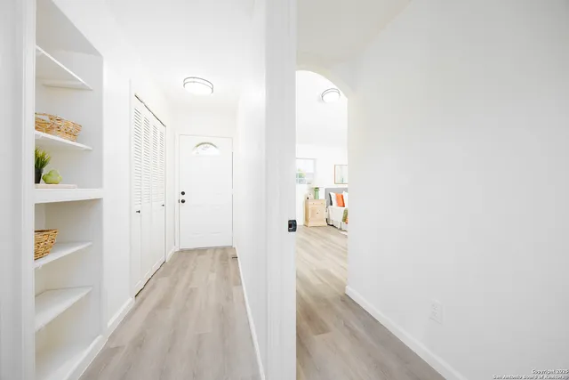 a view of a hallway with wooden floor and a bathroom