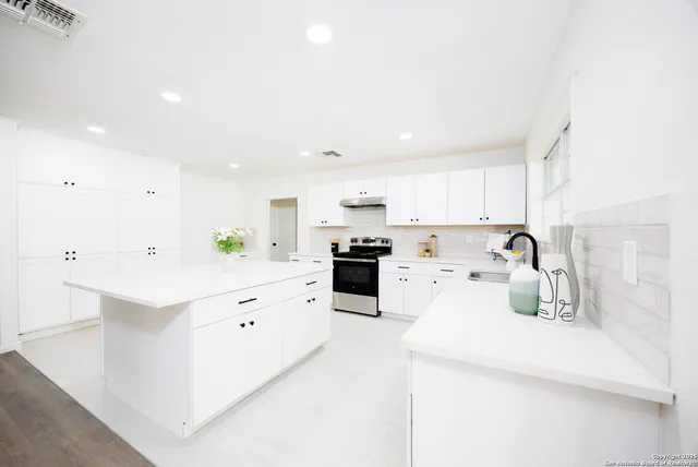 a kitchen with white cabinets and appliances
