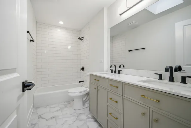 a bathroom with a granite countertop toilet a sink a mirror a bathtub and shower