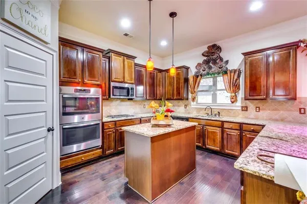 a kitchen with stainless steel appliances granite countertop wooden floors and sink