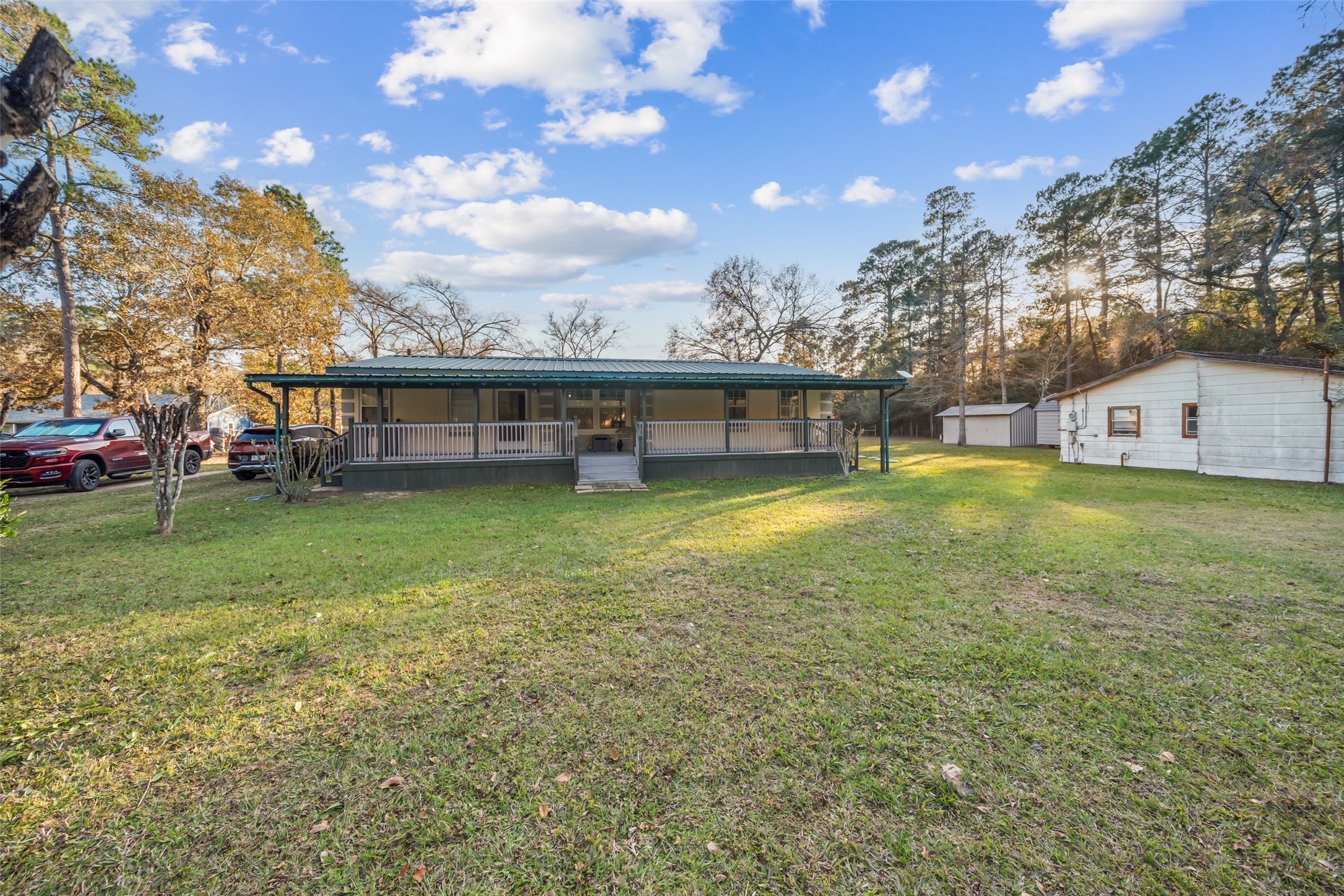 Front view of the home featuring a metal roof, raised pad site, and a large covered front porch. Property sits high and dry with elevation certificate available.