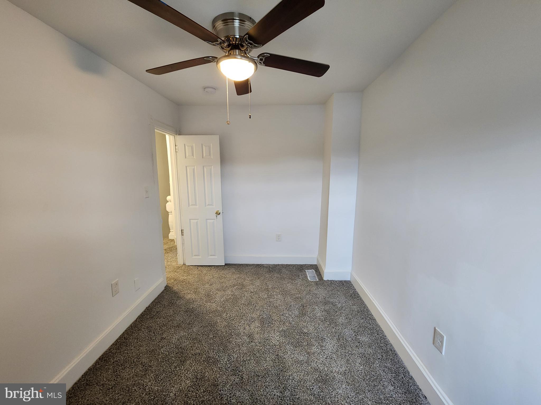 1213 East Lanvale Street Baltimore, MD 21202 - Photo 13 of 22 an empty room with a chandelier fan and windows