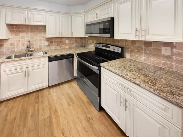 a kitchen with granite countertop white cabinets and white appliances