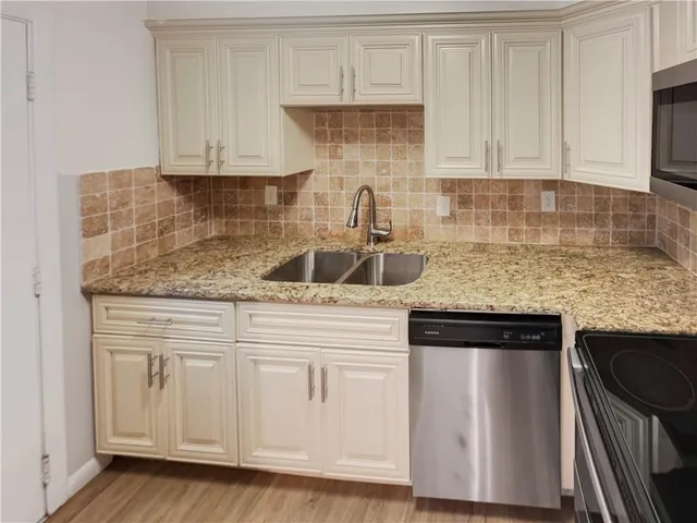 a kitchen with granite countertop white cabinets and a stove