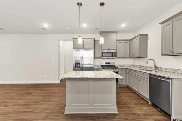 a kitchen with stainless steel appliances granite countertop a sink a stove top oven a counter space and cabinets