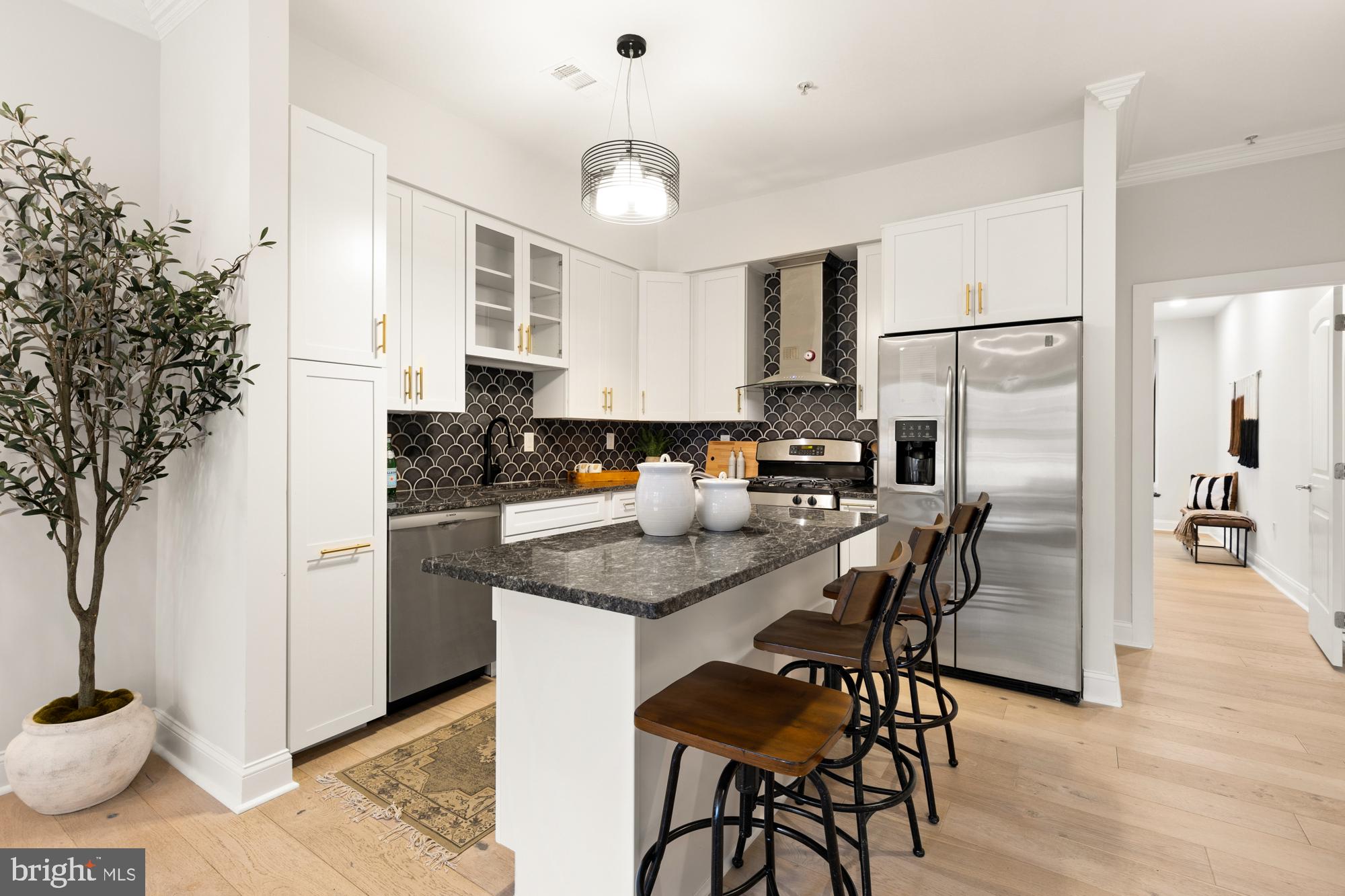 1464 Harvard Street Northwest, Unit 3 Washington, DC 20009 - Photo 15 of 24 a kitchen with stainless steel appliances granite countertop a stove a refrigerator a sink a dining table and chairs with wooden floor