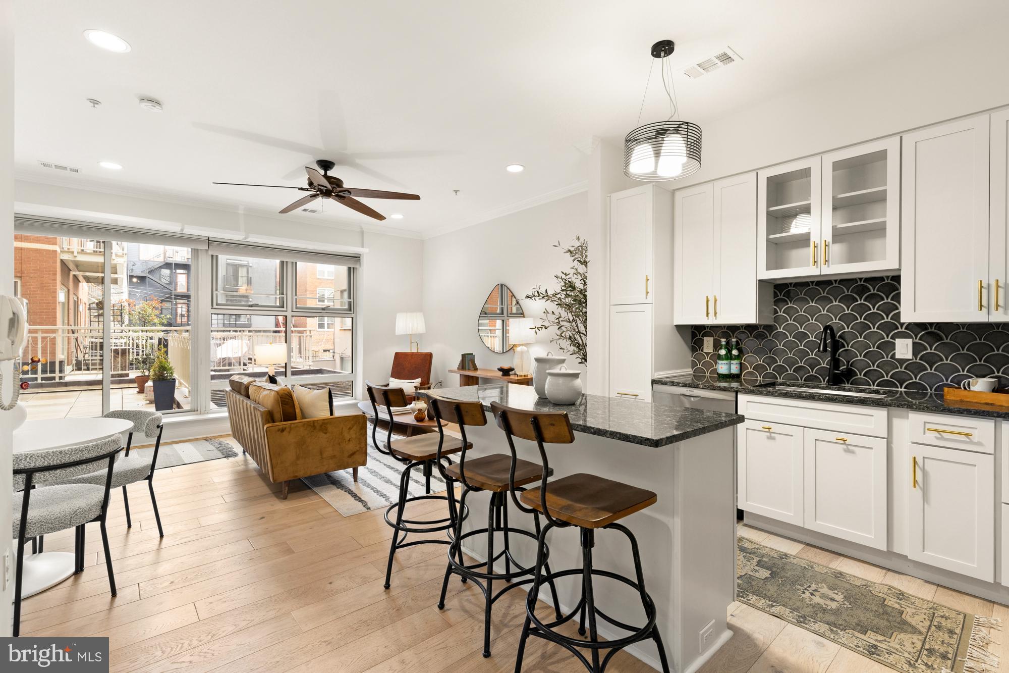1464 Harvard Street Northwest, Unit 3 Washington, DC 20009 - Photo 16 of 24 an open kitchen with granite countertop a stove a sink a dining table and chairs with wooden floor