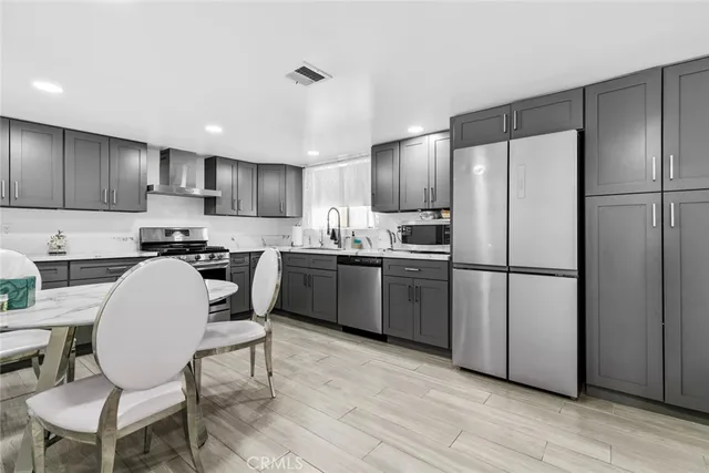 a kitchen with stainless steel appliances a refrigerator a stove a sink and chairs