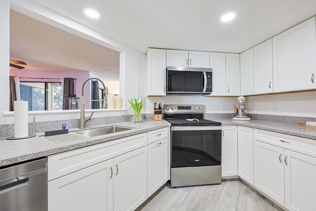276 Trailside Way, Unit 276 Ashland, MA 01721 - Photo 5 of 32 a kitchen with granite countertop a sink stainless steel appliances and white cabinets