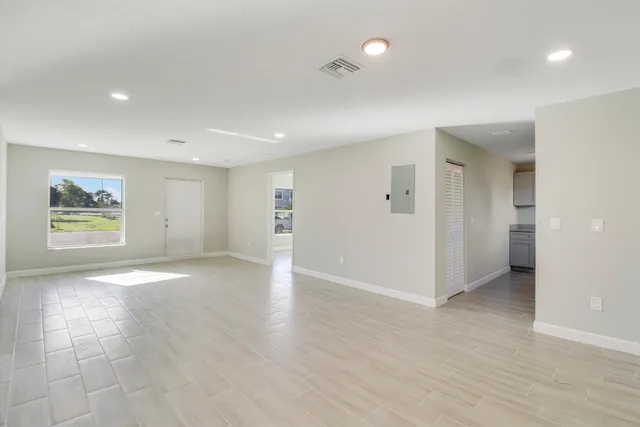 an empty room with wooden floor and windows