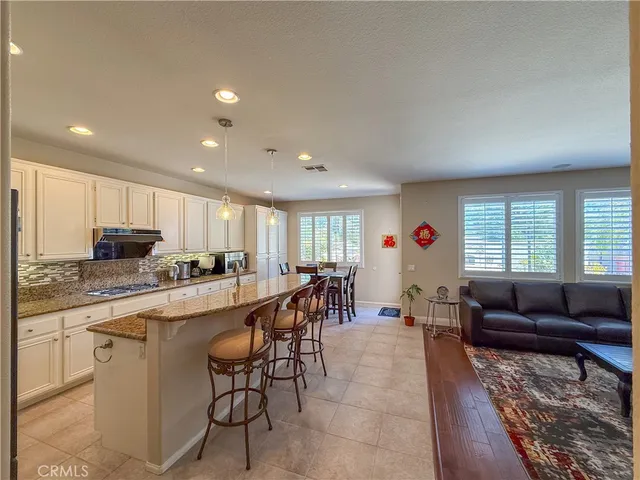 a large living room with stainless steel appliances granite countertop furniture a rug a stove and a window