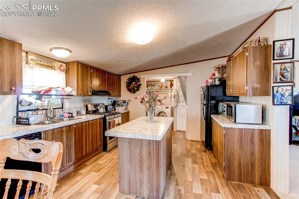 5955 Mulberry Road Calhan, CO 80808 - Photo 6 of 25 a kitchen with stainless steel appliances granite countertop a refrigerator a sink dishwasher a stove and a dining table with wooden floor