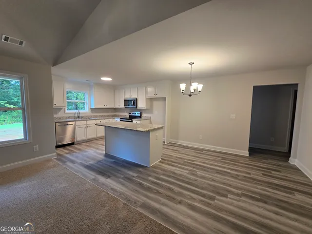 an empty room with kitchen view and wooden floor