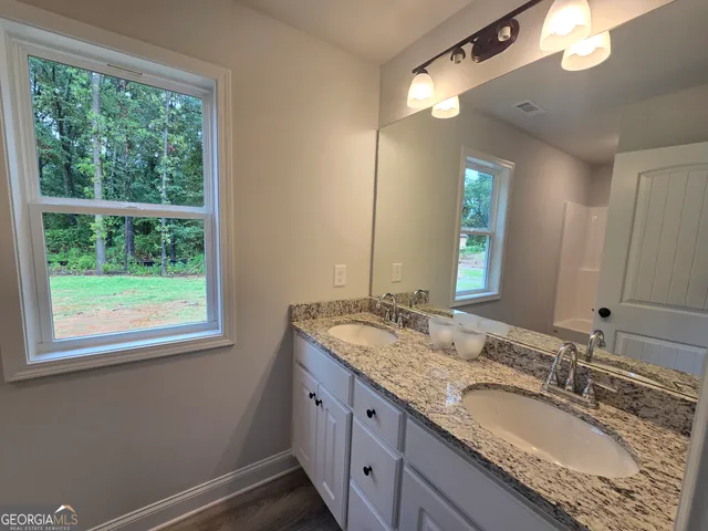 a bathroom with a granite countertop sink a large mirror and a window