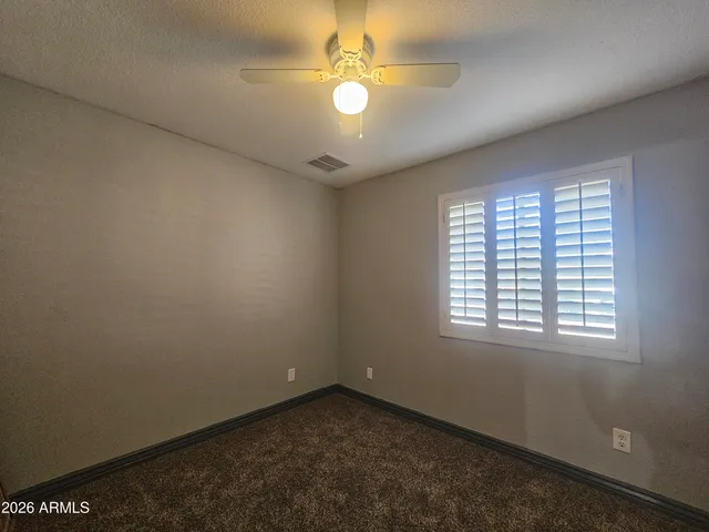 an empty room with a window and a fan