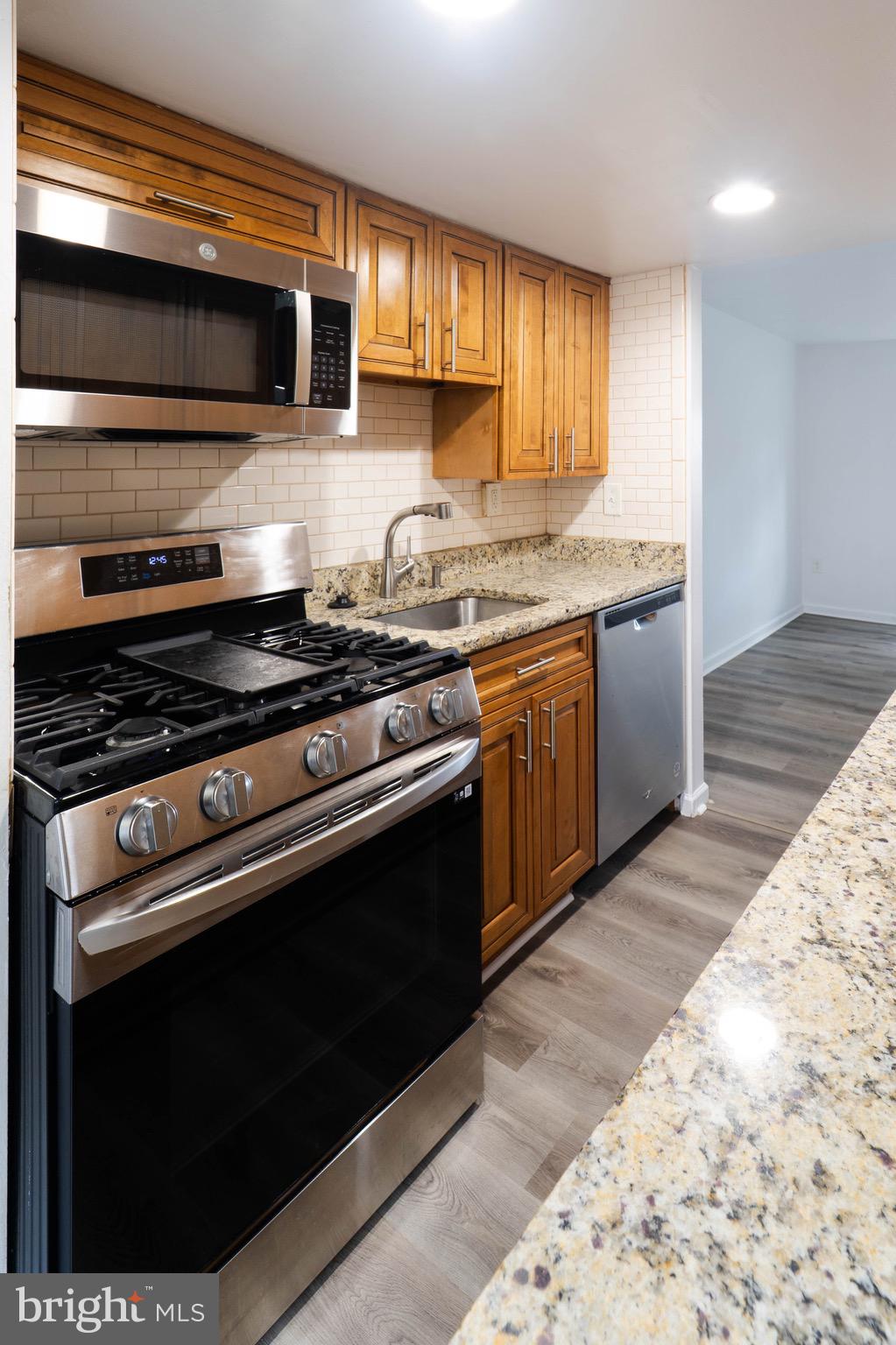 9318 Matador Road Columbia, MD 21045 - Photo 10 of 32 a kitchen with stainless steel appliances kitchen island granite countertop wooden cabinets stove top oven and sink