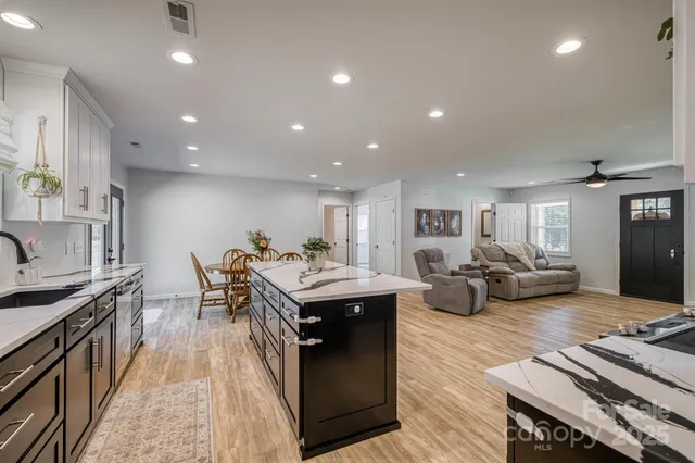 a living room with furniture a rug kitchen view and a faucet
