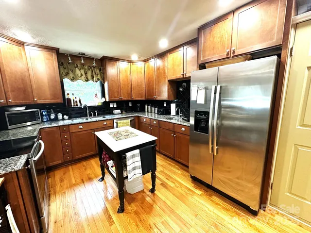a room with stainless steel appliances lots of wooden furniture