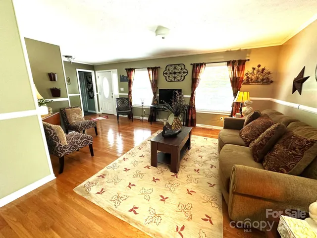 a living room with furniture hard wood floor and a flat screen tv