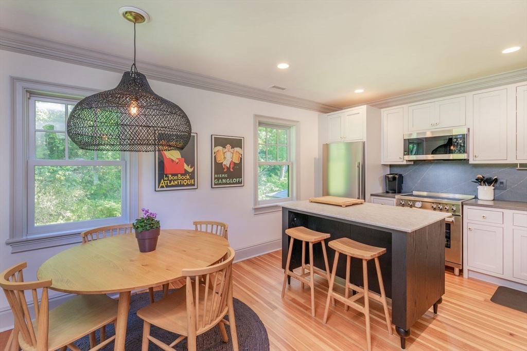 450 Summer Street Manchester, MA 01944 - Photo 30 of 42 a kitchen island with stainless steel appliances granite countertop a stove a sink dishwasher a dining table and chairs with wooden floor