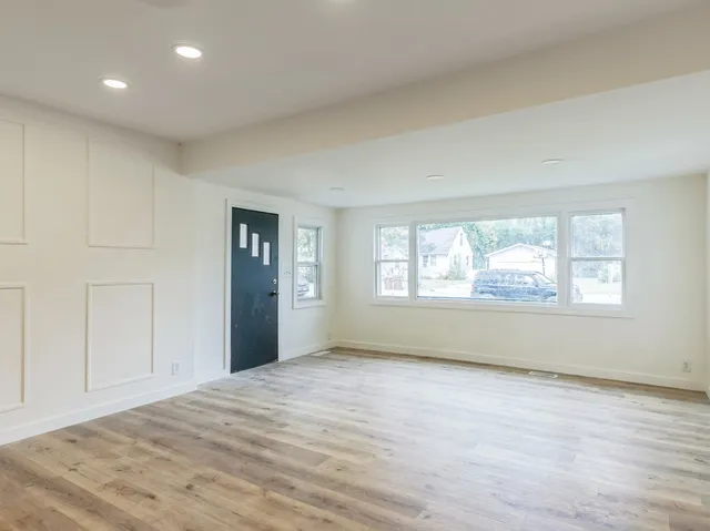 a view of an empty room with wooden floor and windows