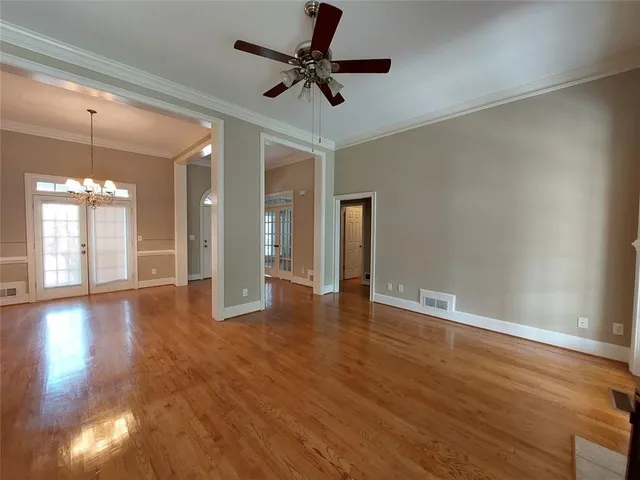 a view of an empty room with window and wooden floor