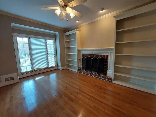 a view of an empty room with wooden floor fireplace and a window