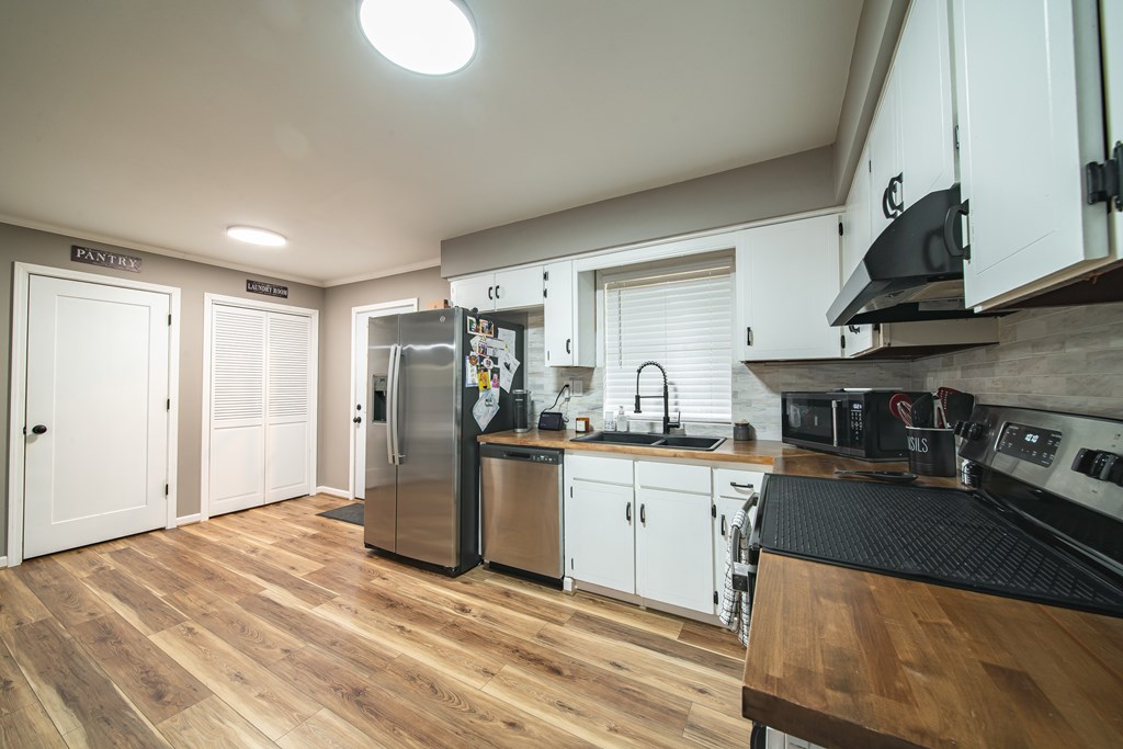 6315 Rockefeller Drive Columbus, GA 31909 - Photo 6 of 24 a kitchen with stainless steel appliances granite countertop a refrigerator a sink dishwasher a stove with white cabinets and wooden floor