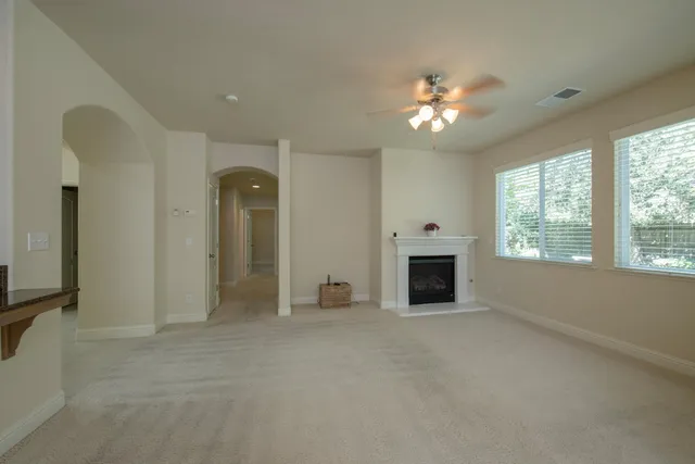 an empty room with chandelier fan and windows