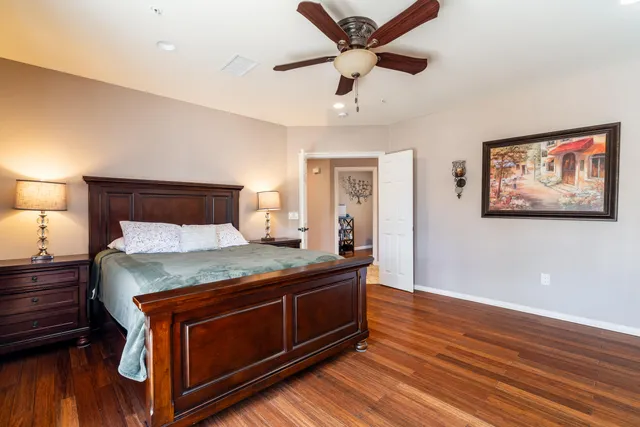 a bed sitting in a spacious bedroom and night stand