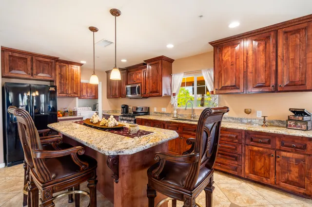 a table and chairs in a kitchen with granite countertop wooden cabinets