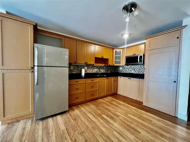 a kitchen with stainless steel appliances granite countertop a refrigerator a sink and white cabinets