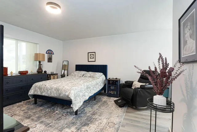a bedroom with a bed and a potted plant on dresser